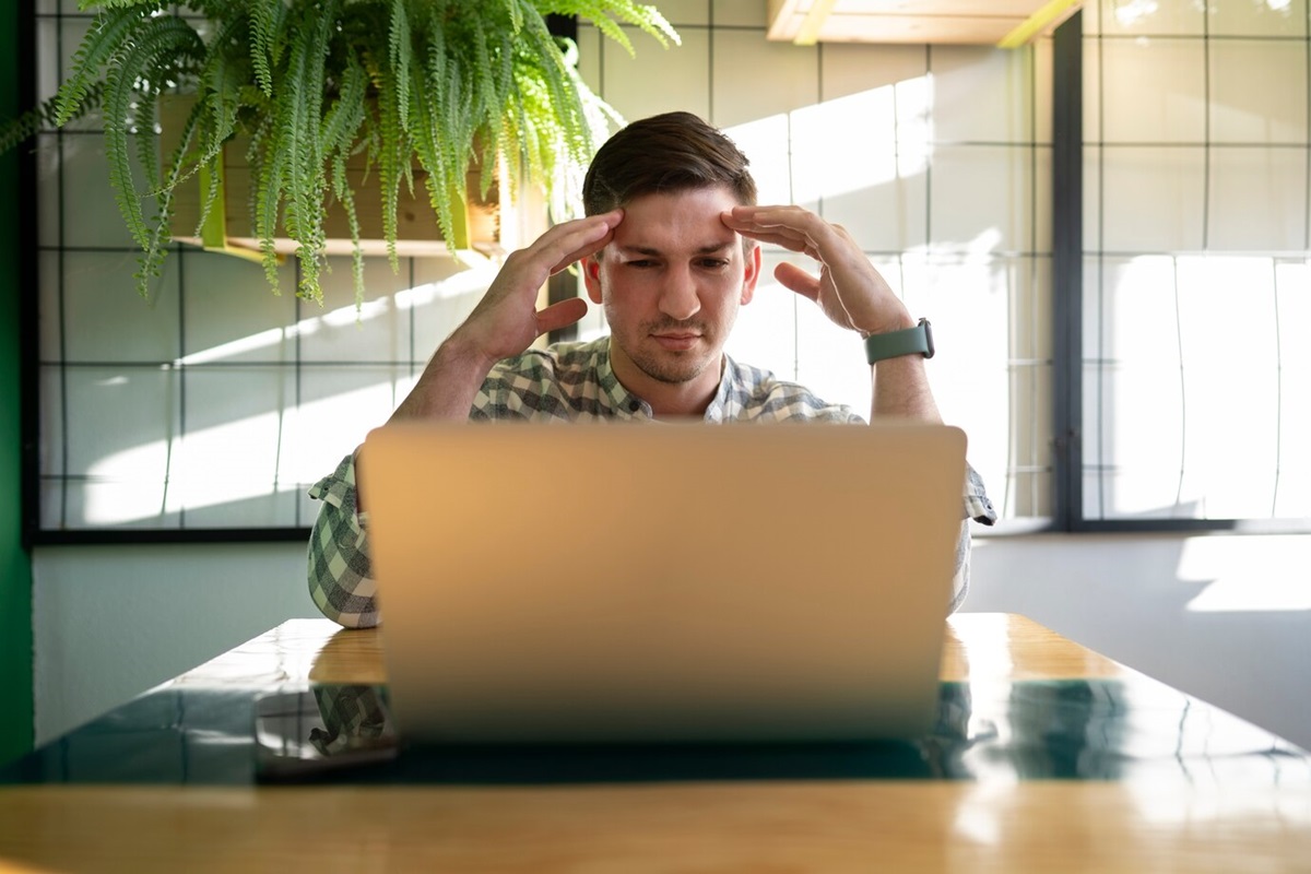 Homem frustrado com as mãos na cabeça enquanto usa um computador com Windows lento.