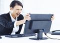 Mulher irritada gritando com o PC (computador) que travou no ambiente de trabalho.