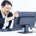 Mulher irritada gritando com o PC (computador) que travou no ambiente de trabalho.