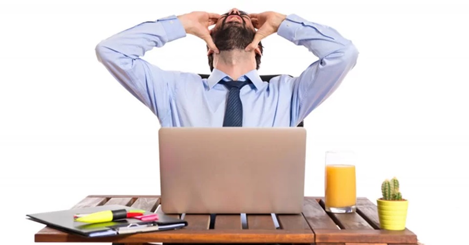 Homem irritado com o notebook que travou no ambiente de trabalho.