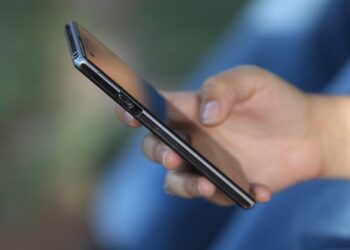 Pessoa segurando um smartphone moderno e limpando o cache para melhorar desempenho do celular.