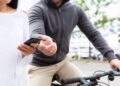 Pessoa tendo o celular roubado por outra enquanto está montada em uma bicicleta, em um ambiente urbano.