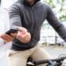 Pessoa tendo o celular roubado por outra enquanto está montada em uma bicicleta, em um ambiente urbano.